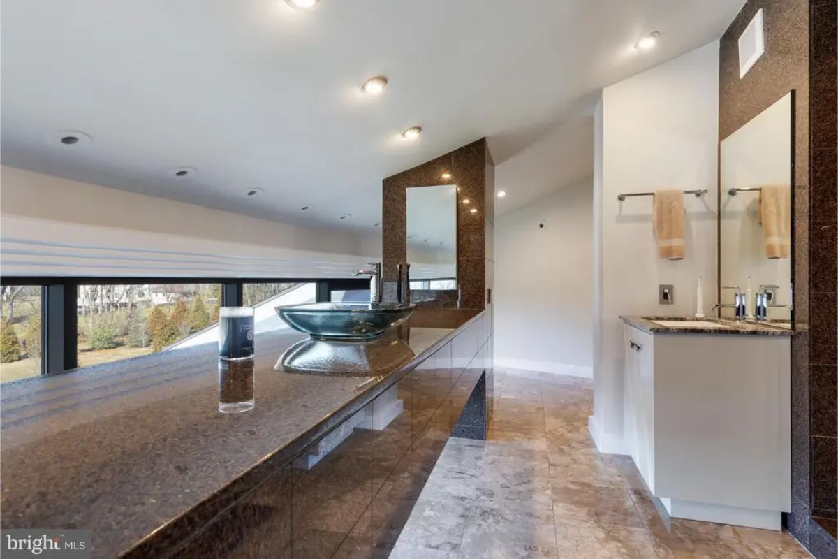 Bathroom design includes a sleek vessel sink on a granite countertop with panoramic views. 