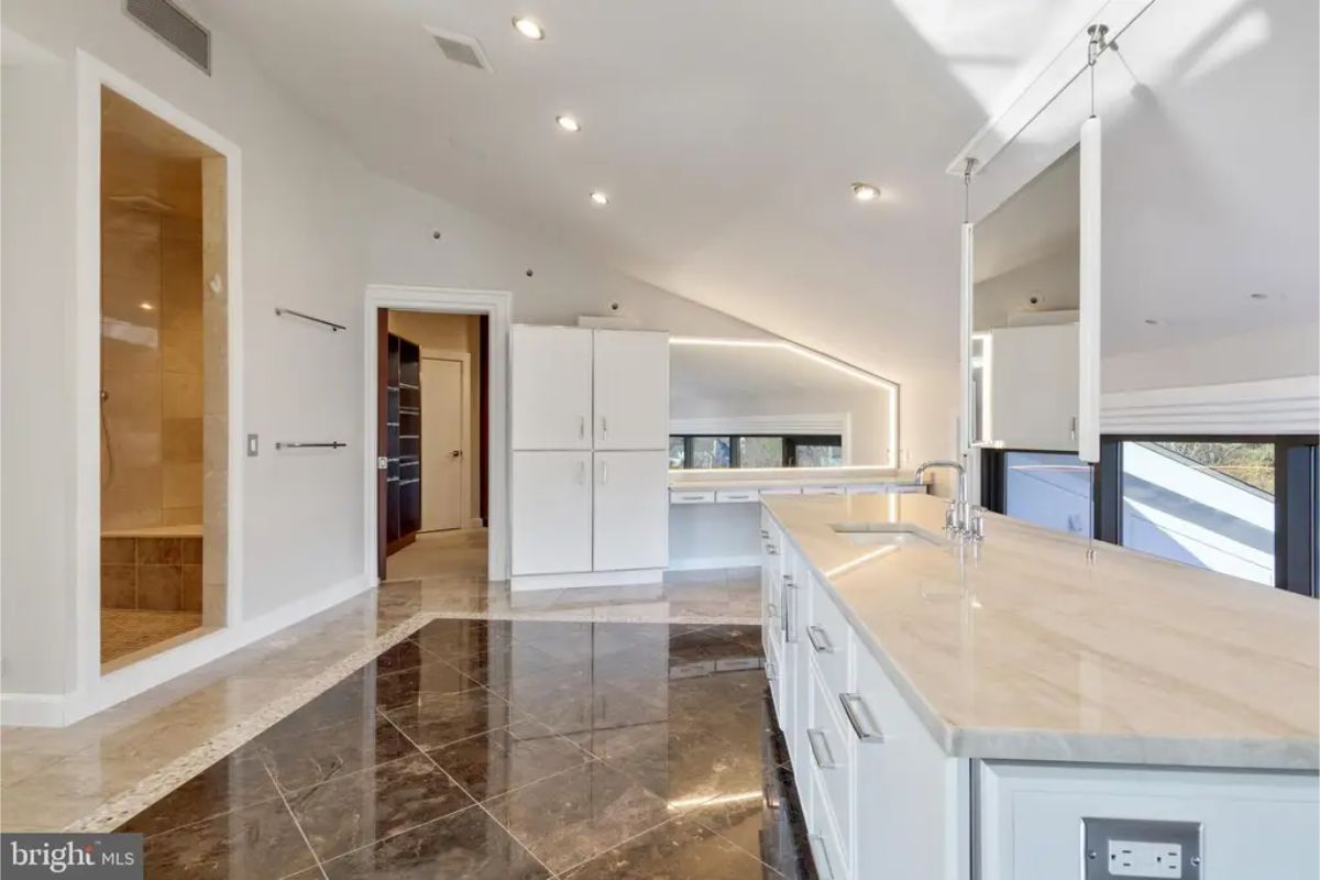 Spacious bathroom showcases double sinks, bright white cabinetry, and a walk-in shower. 