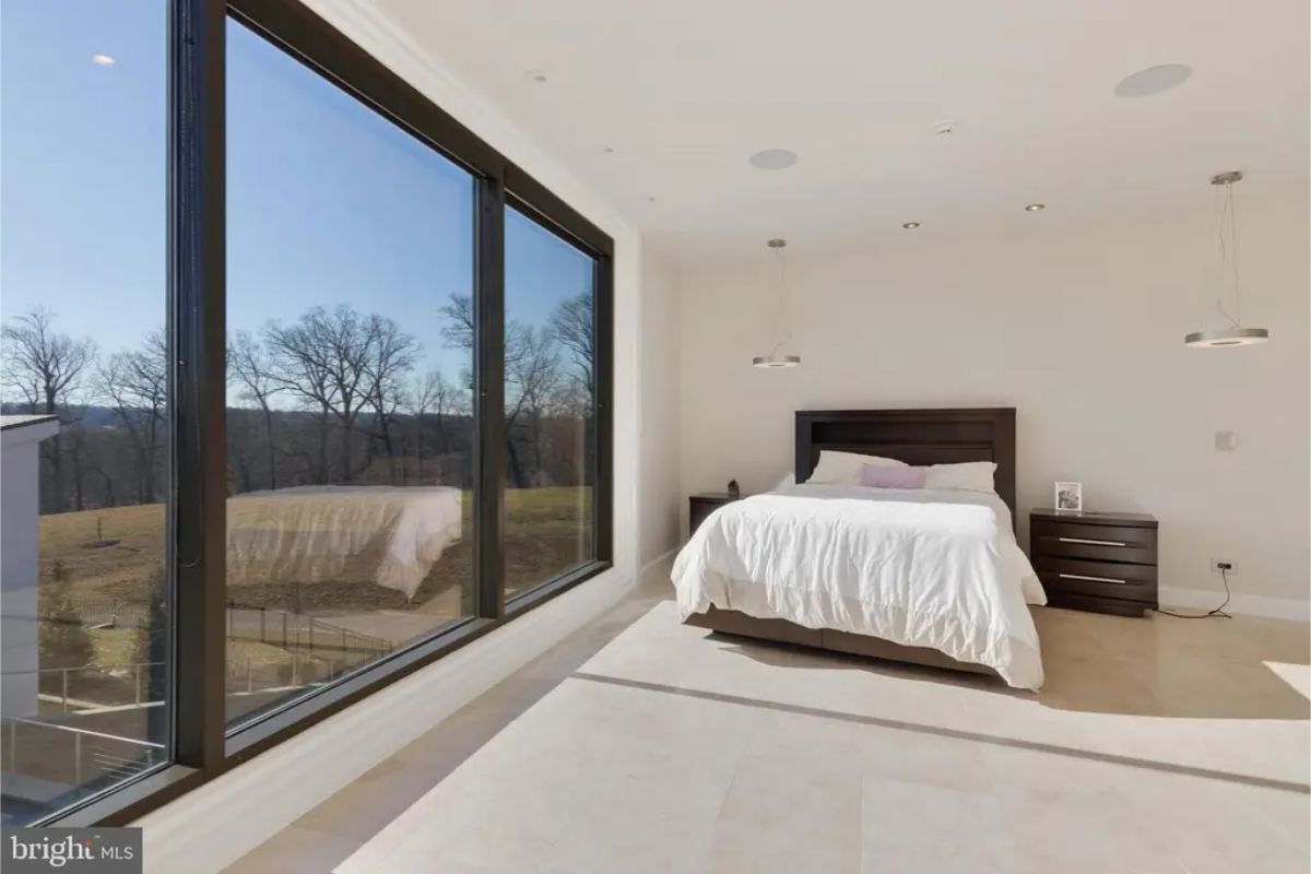 Bedroom features a large window with a scenic view of trees and landscape. 