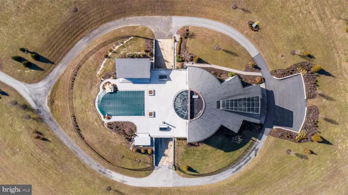 Aerial view displays the unique architectural layout of the home, including the circular central design and surrounding landscape. 