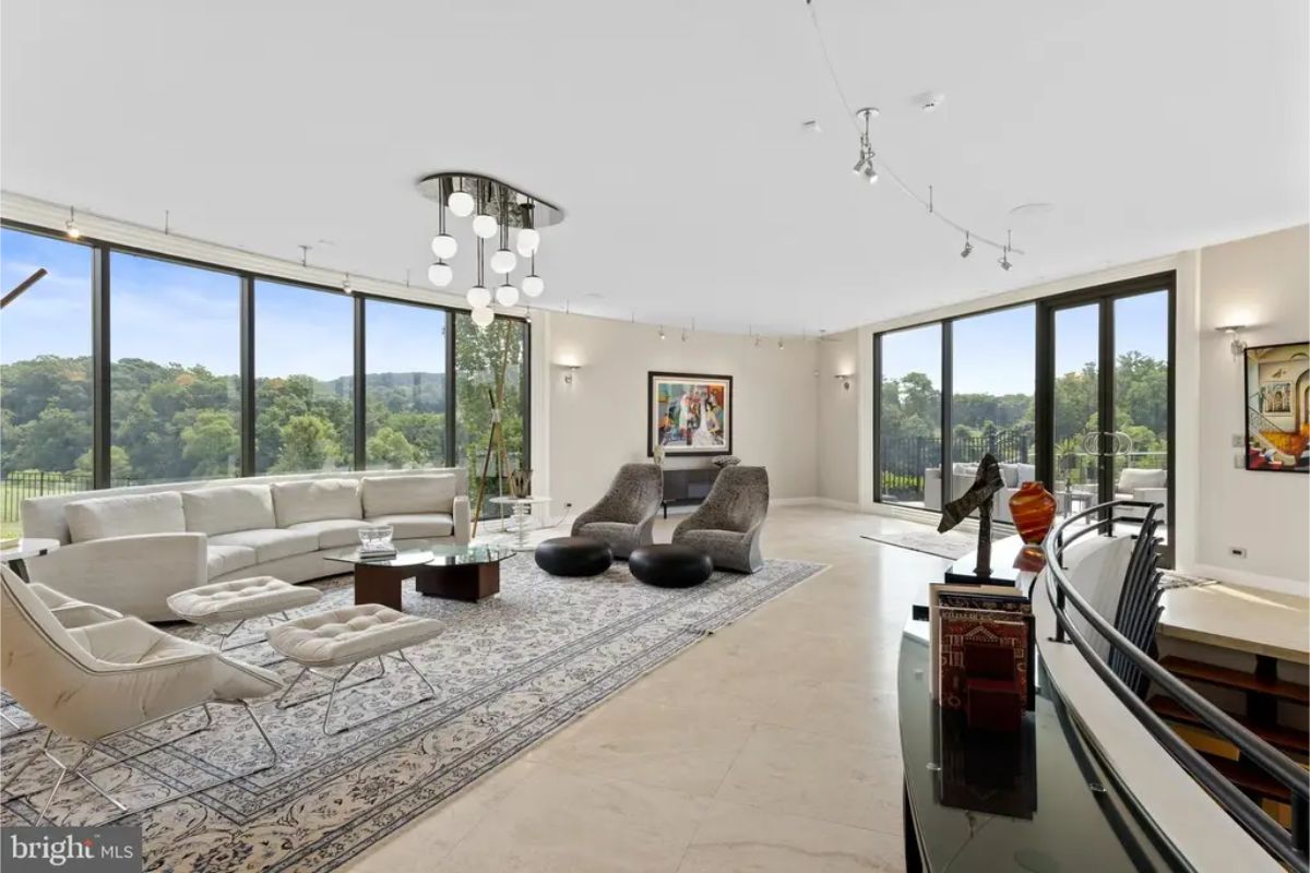 Living area featuring large sectional sofa, modern armchairs, and expansive natural light. 