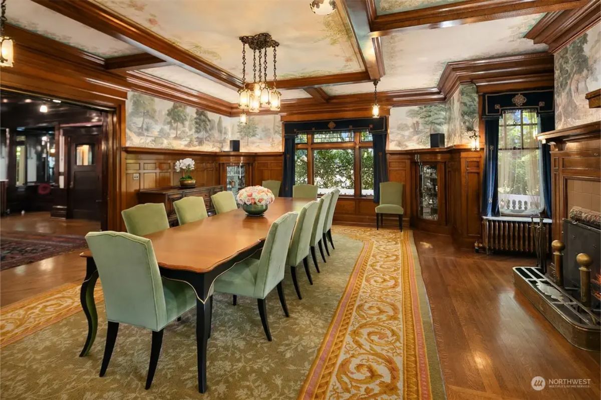 A long table surrounded by green upholstered chairs.