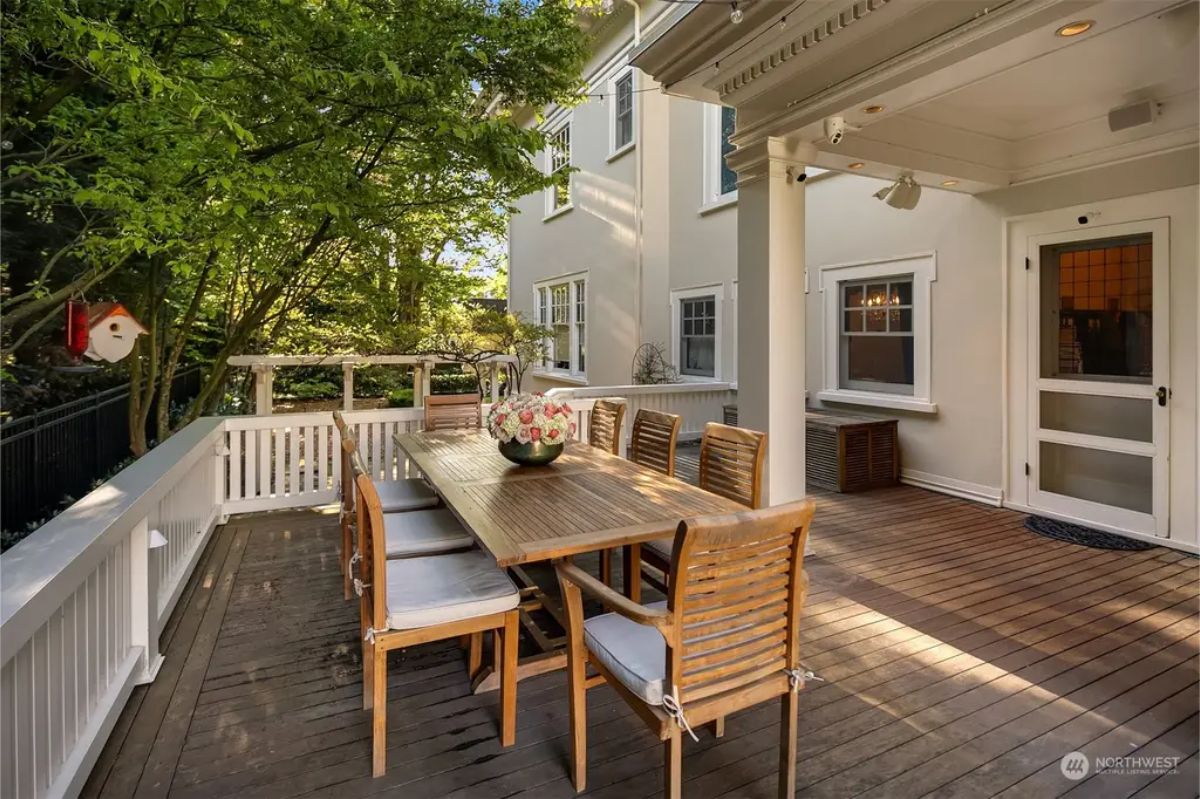Wooden deck features a large dining table with cushioned chairs for outdoor gatherings.