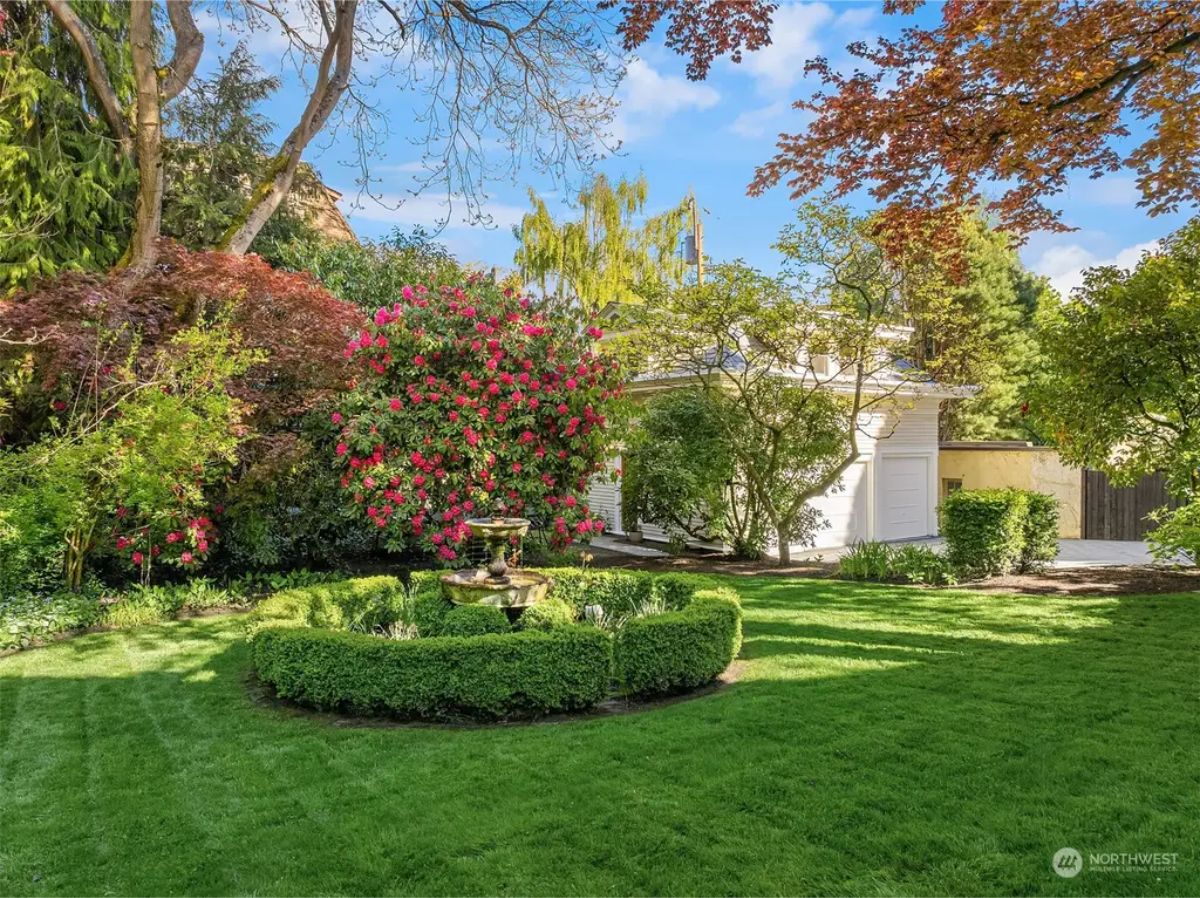 Vibrant garden features a central fountain surrounded by a trimmed hedge.