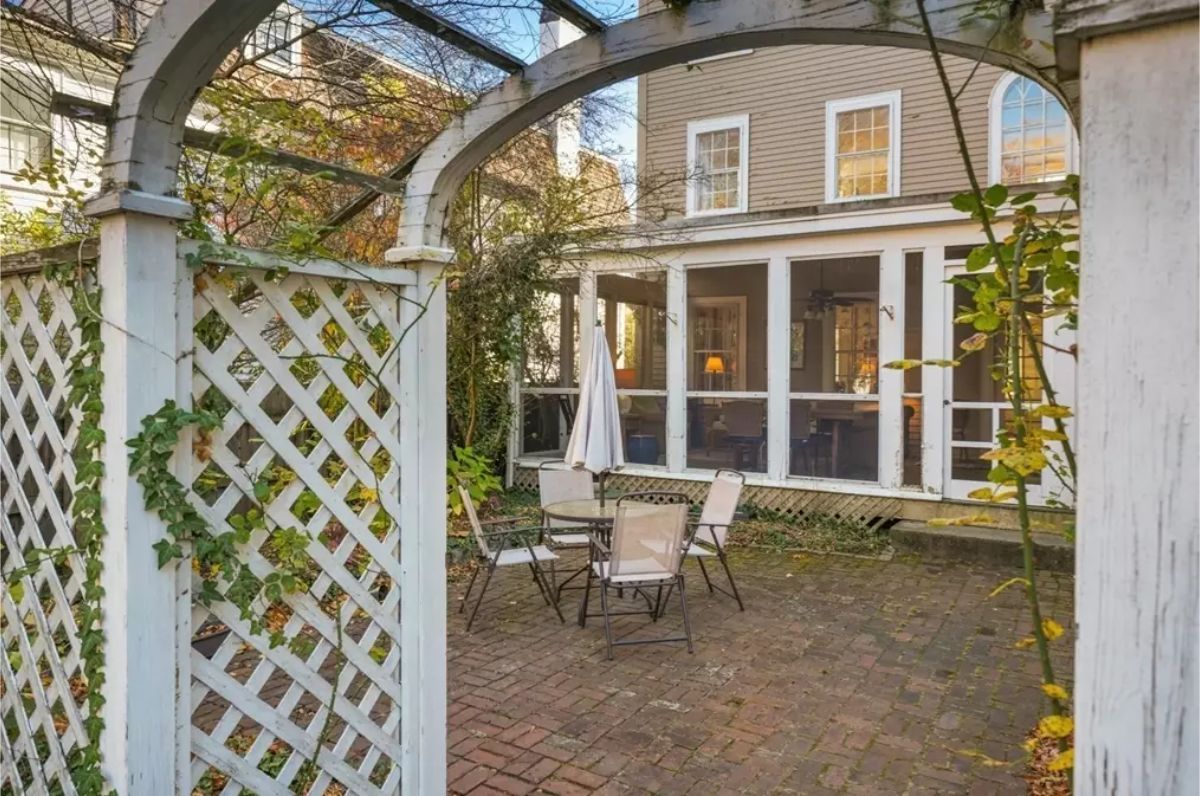This quaint outdoor patio features a brick-paved seating area surrounded by lush greenery, creating a peaceful retreat.