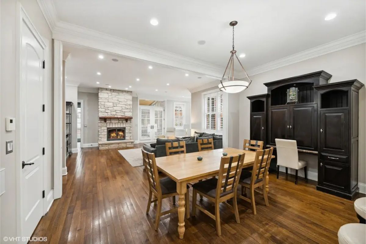 Hardwood floors and neutral walls a stone fireplace serves as the focal point of the living space, surrounded by comfortable seating.