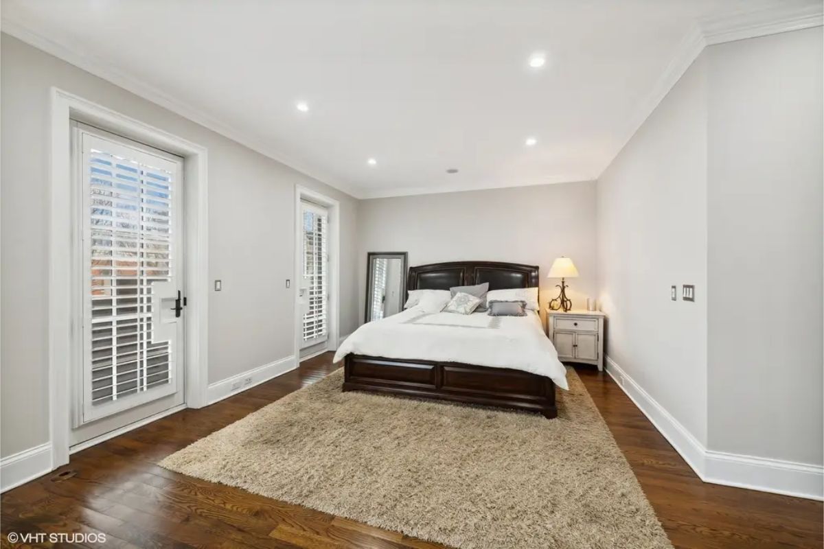 Light walls, recessed lighting, and natural light streaming through glass doors with plantation shutters.