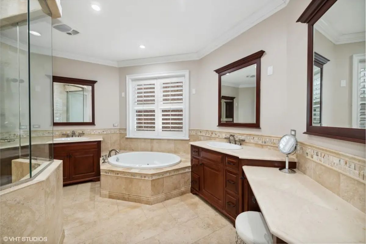 Central whirlpool tub surrounded by natural stone tile.