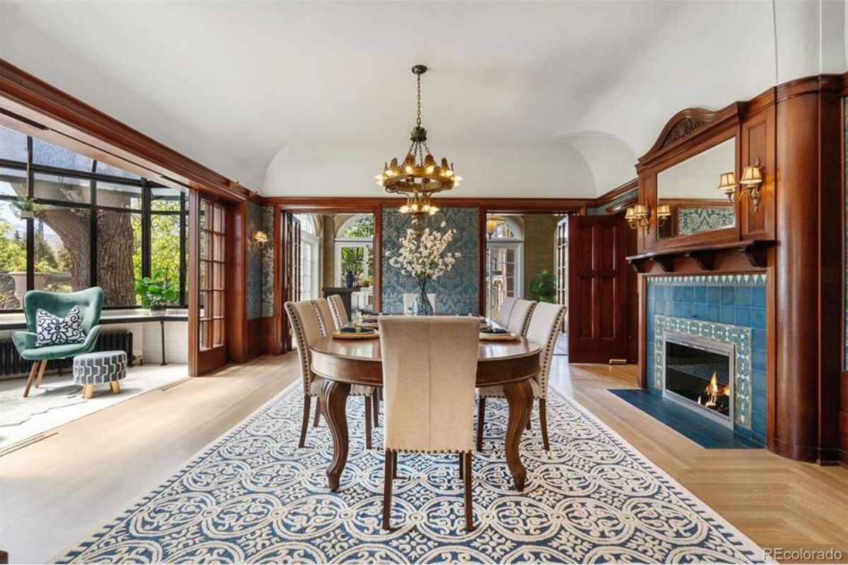 Dining room exudes historic charm, featuring a fireplace adorned with intricate Van Briggle tile and rich wood-paneled walls.