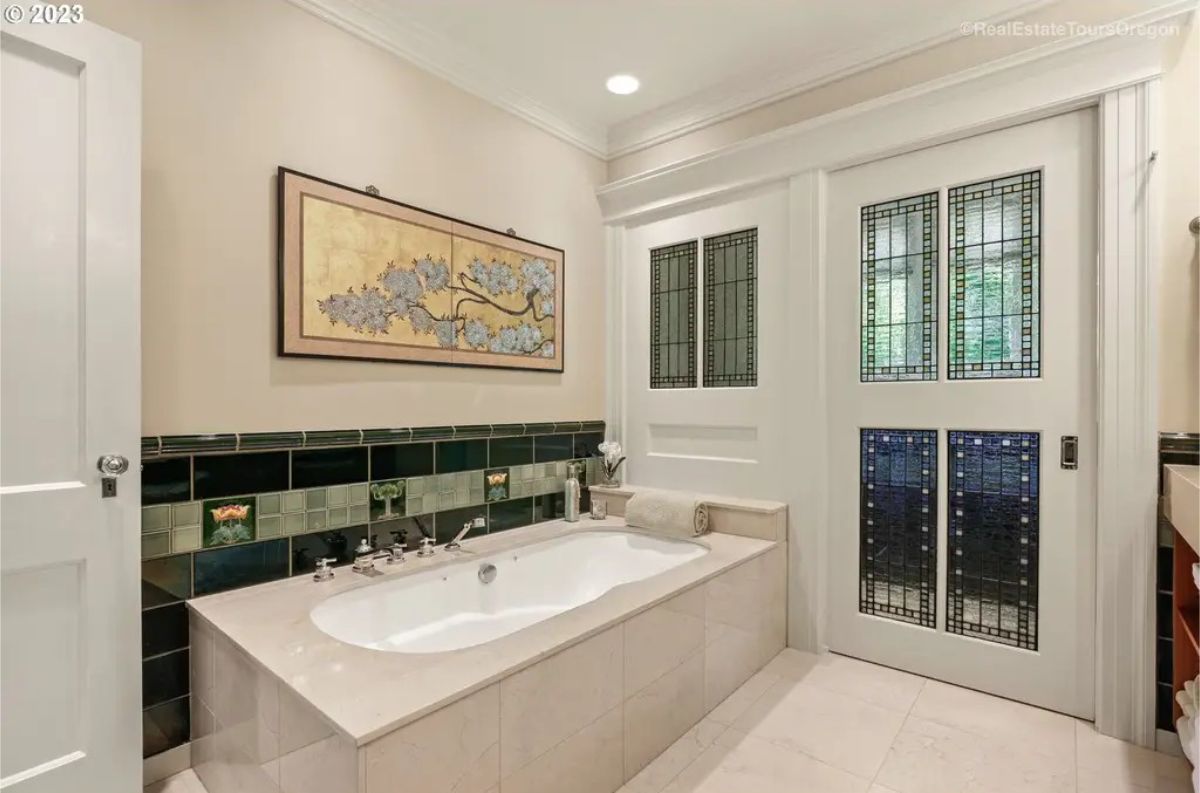 Deep soaking tub framed by glossy green and patterned tiles.