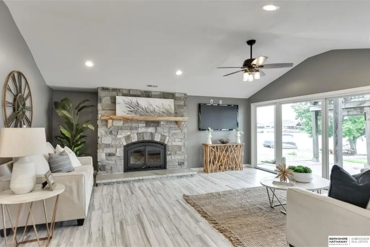 Living room designed with a large stone fireplace and wooden mantel as the focal point.