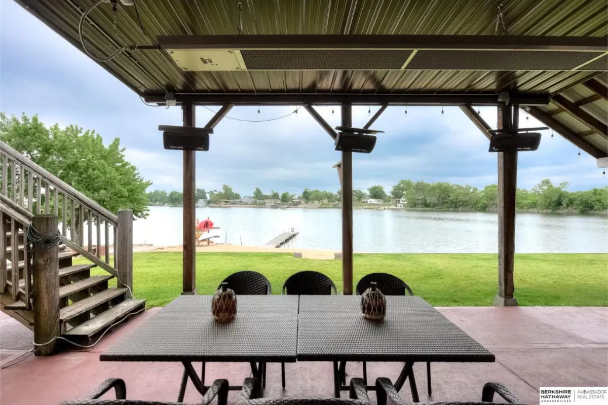 Covered patio overlooking a tranquil lake, providing an ideal setting for outdoor dining and relaxation.