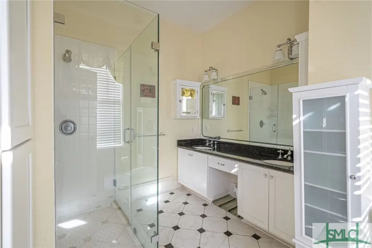 Bathroom featuring a walk-in glass shower with tiled walls and natural light from a nearby window.