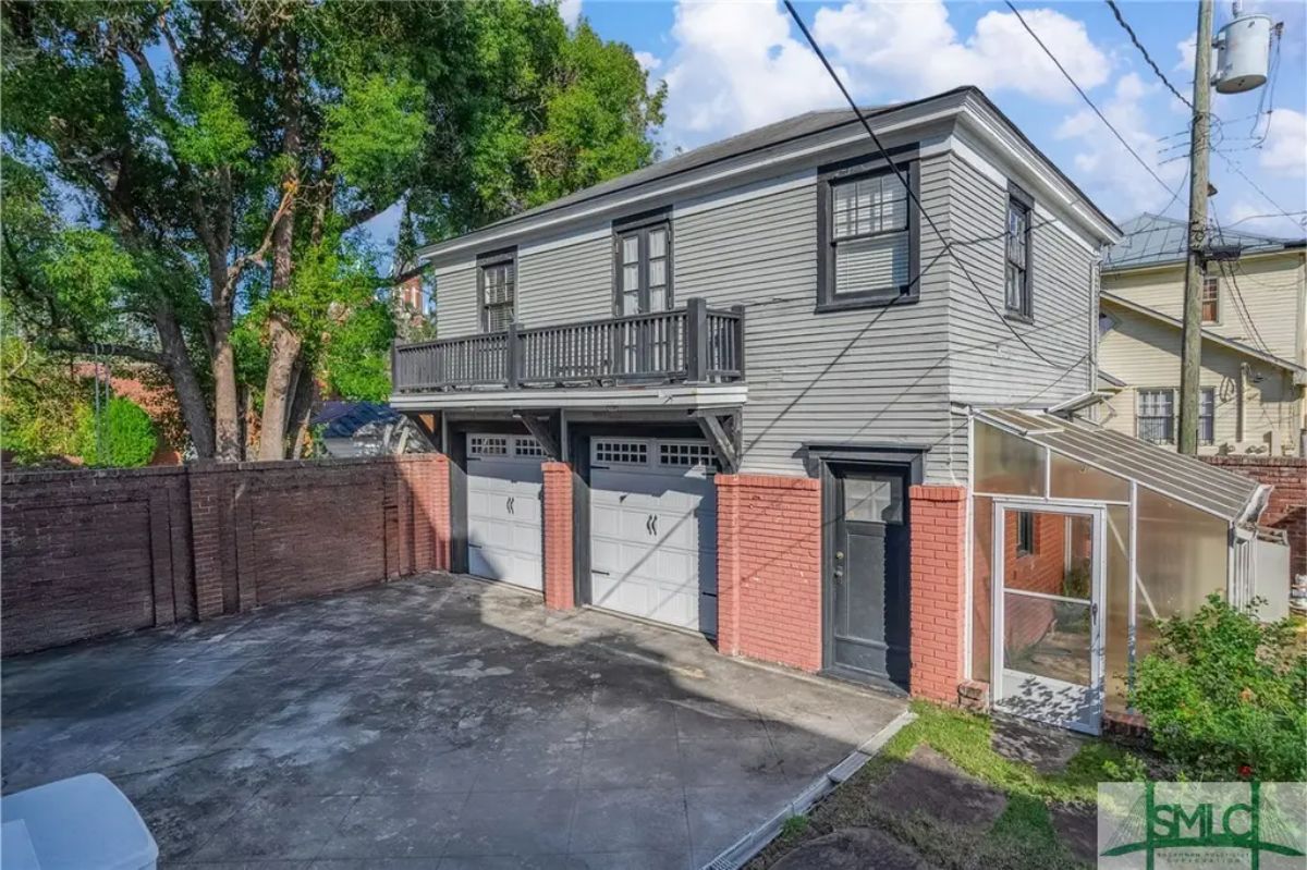 Detached garage with two-car capacity,gardening featuring red brick accents and a gray exterior.