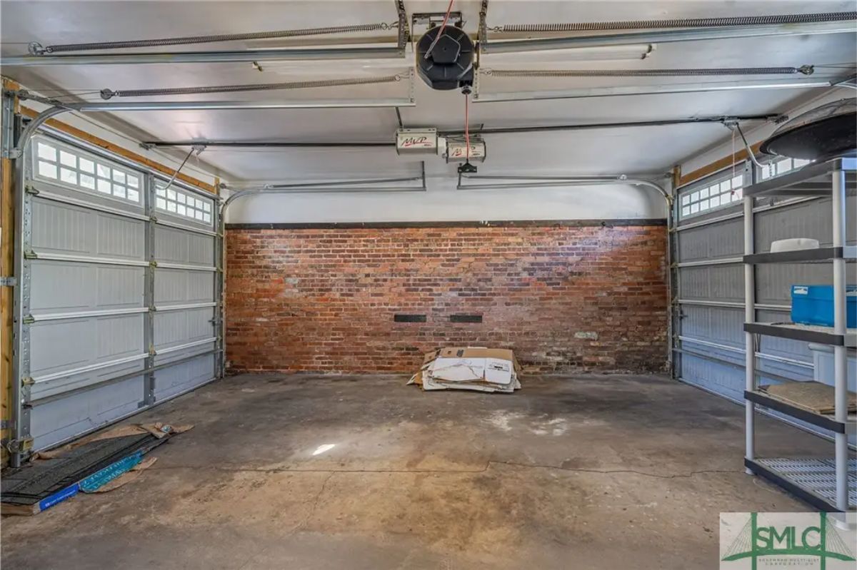 Two-car garage featuring exposed brick on one wall, adding character to the functional space.