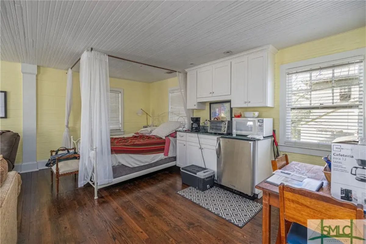 Efficient studio space featuring a cozy sleeping area with a canopy bed and privacy curtains.