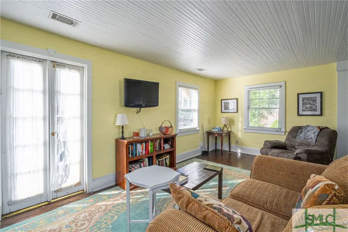 Bright living room with yellow walls and beadboard ceiling creating a cheerful atmosphere.