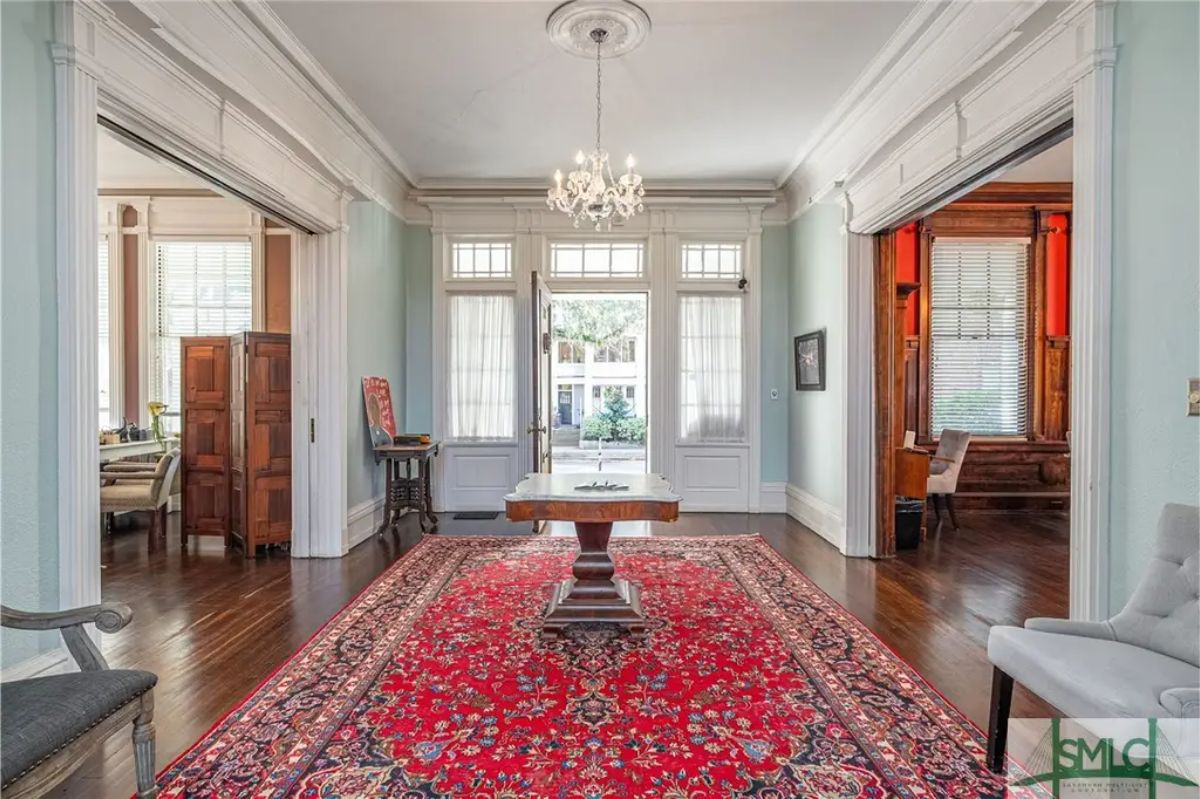 Entry hall showcasing high ceilings, detailed crown molding, and large windows with transom panels.