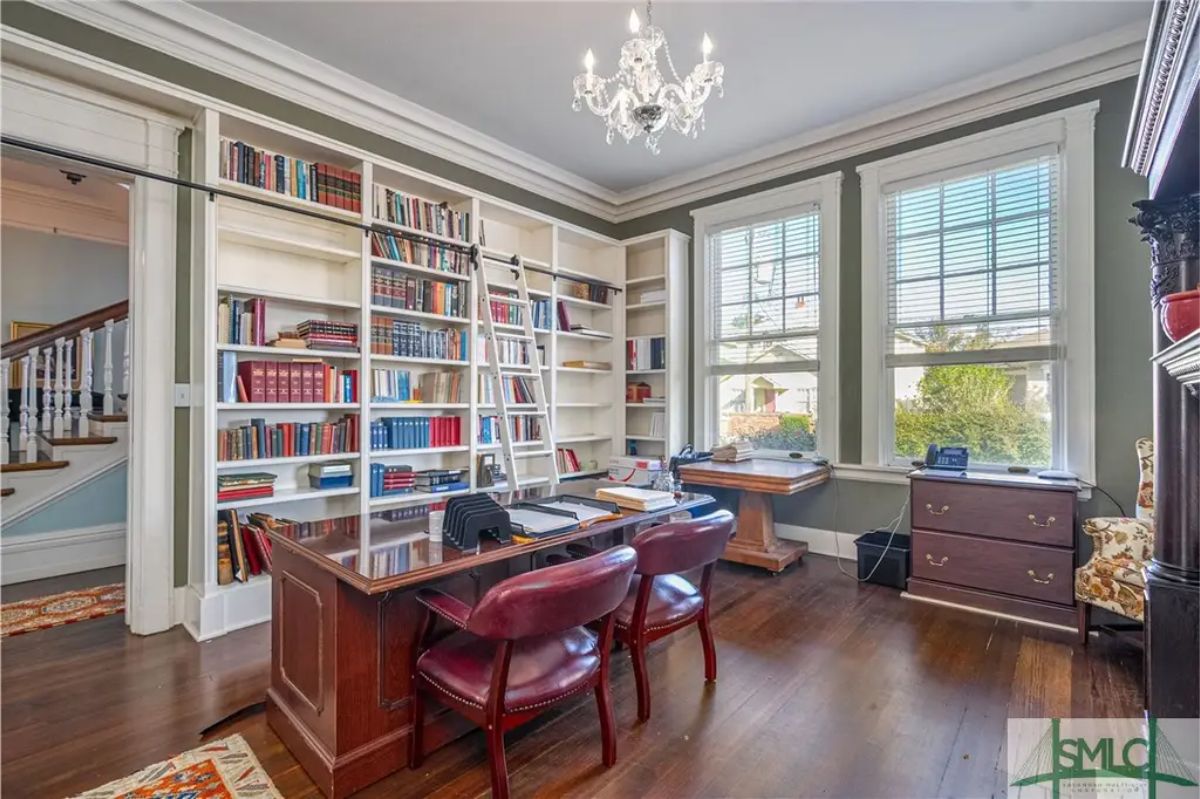 Bright library with floor-to-ceiling built-in bookshelves and a rolling ladder for easy access.