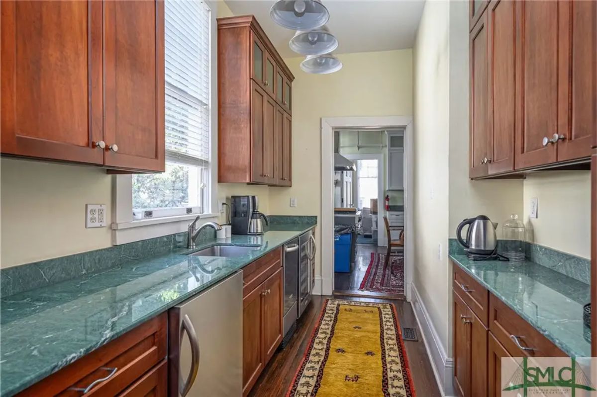 Compact galley kitchen featuring dark wood cabinets and green countertops for a warm, functional design.
