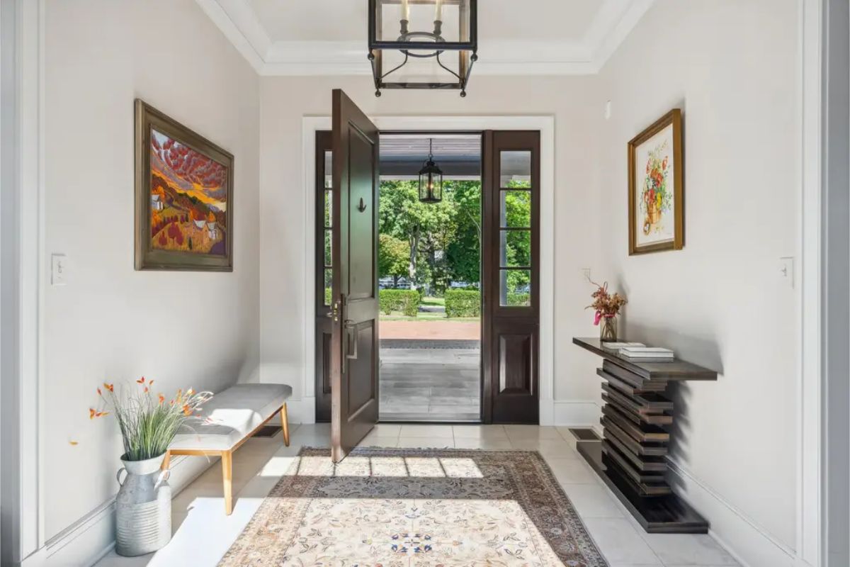 Natural light streaming through large glass doors. Neutral walls are complemented by framed artwork and a patterned rug.