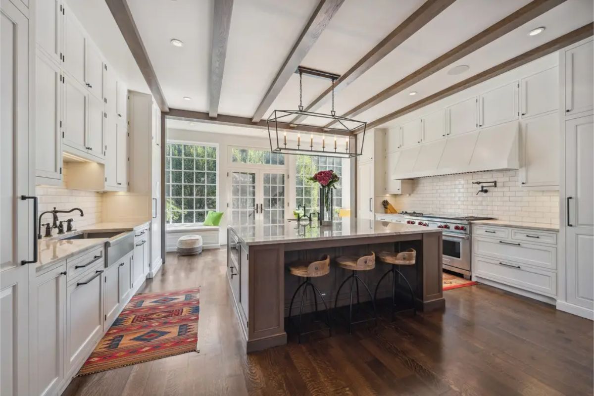 Exposed wood beams, white cabinetry, and a large central island.