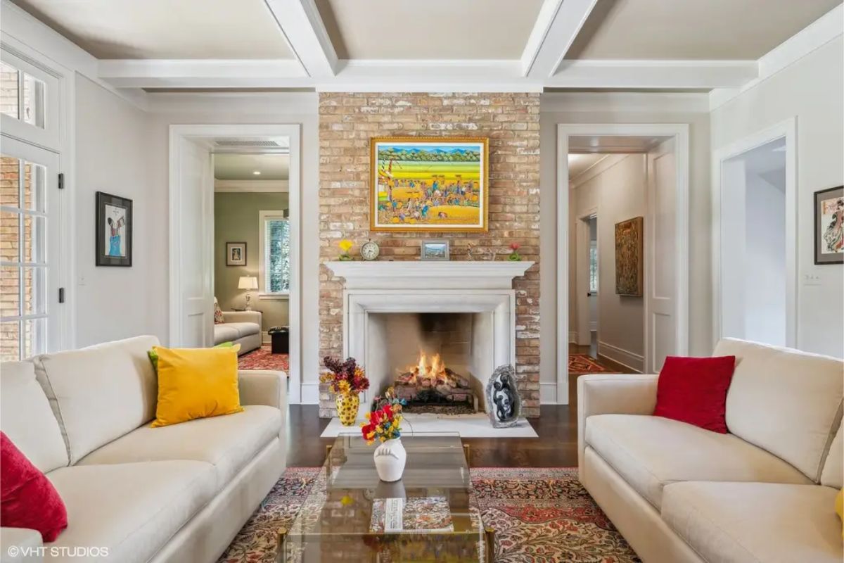 Central brick fireplace surrounded by light walls and a coffered ceiling.