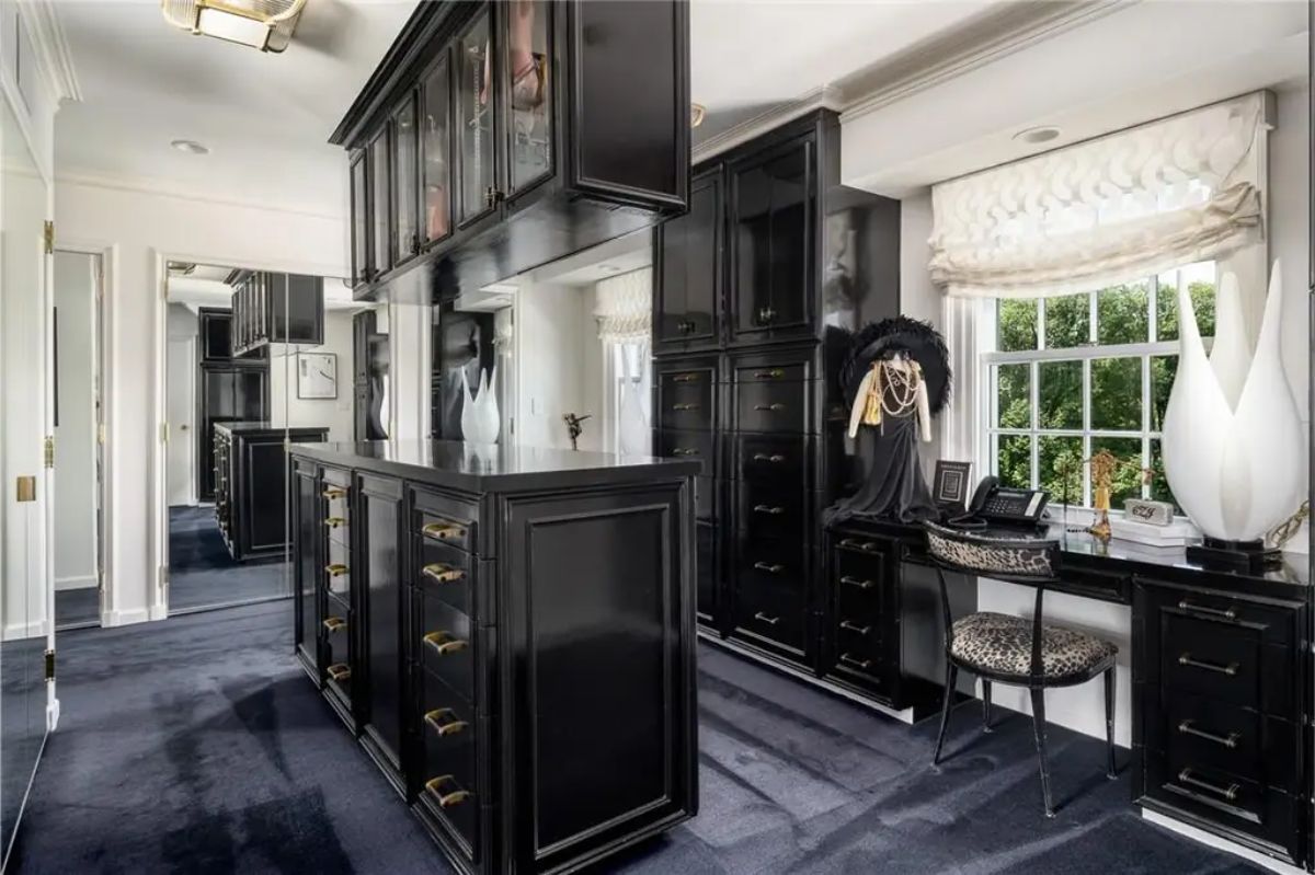 Walk-in closet showcases black cabinetry, a mirrored ceiling, and a small work desk. 