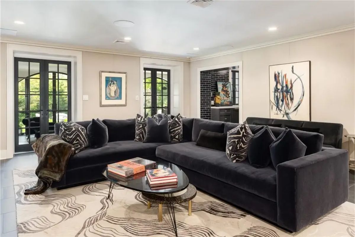 Modern entertainment area with a dark sectional sofa, bold artwork, and access to a patio. 