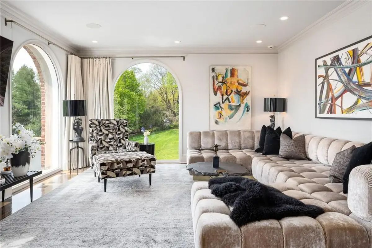 Contemporary living room featuring large arched windows, abstract artwork, and plush seating. 