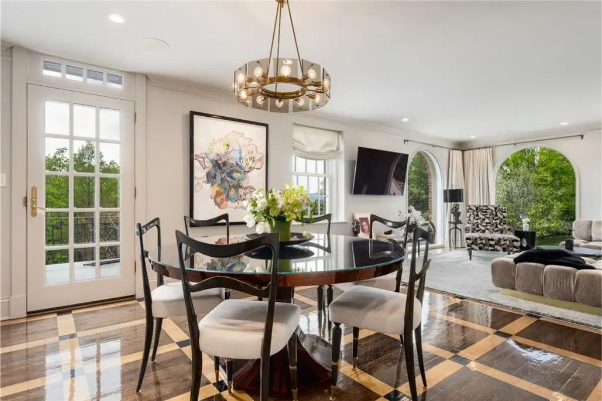 Breakfast nook with a round black table, modern lighting, and arched windows offering garden views. 