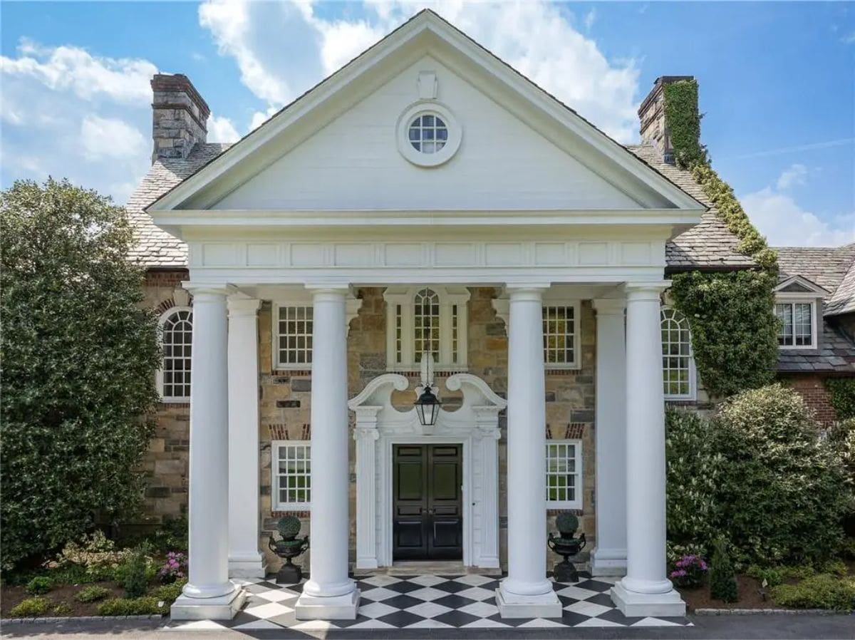 Front entrance showcasing classical columns, symmetrical design, and a black-and-white tiled entryway. 
