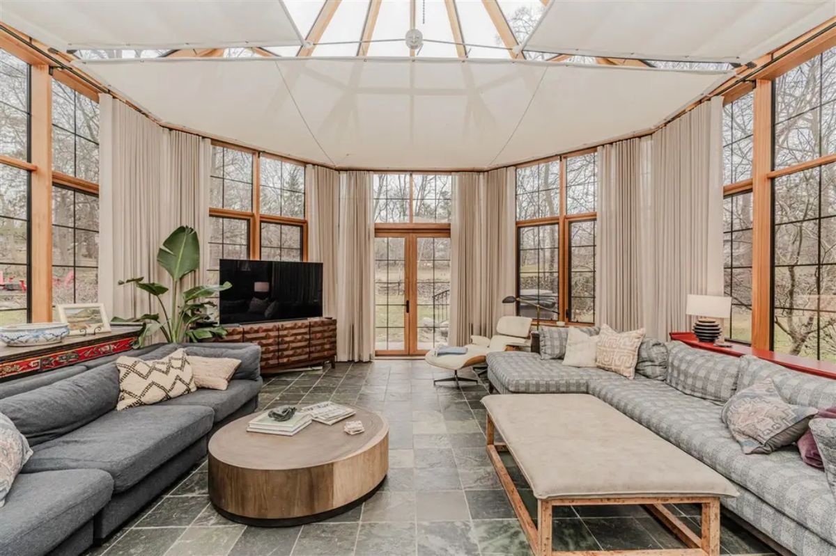 Floor-to-ceiling windows framed in natural wood, offering panoramic views of the outdoors.