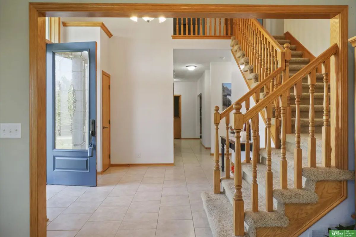 Two-story foyer leads to an open staircase with wooden railings, setting a welcoming tone for the home.