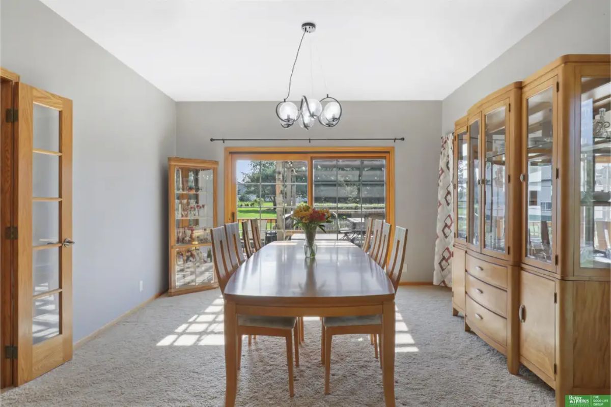 Dining room showcases a spacious wooden table surrounded by matching chairs, perfect for family gatherings.