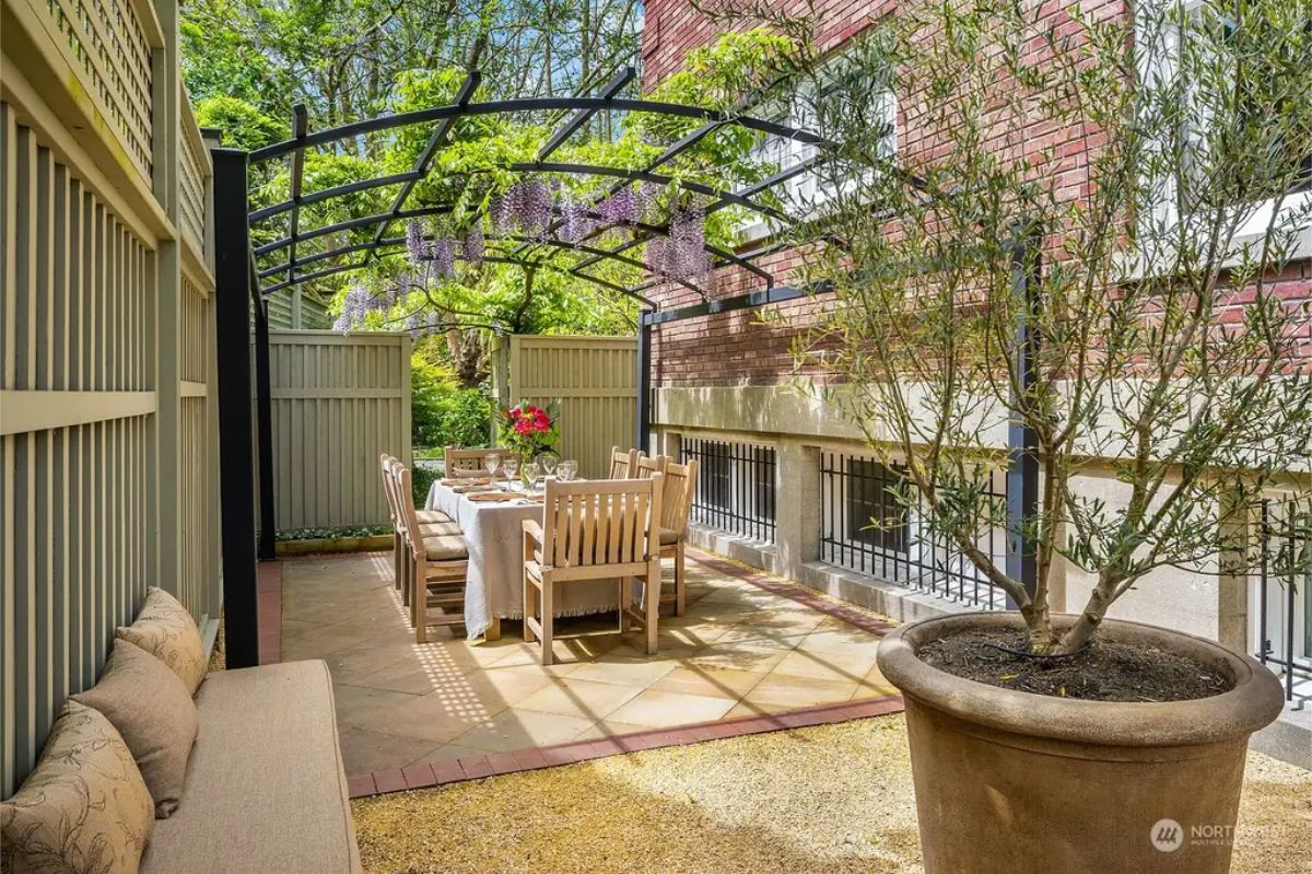 Intimate patio features a dining table surrounded by wooden chairs for al fresco meals.