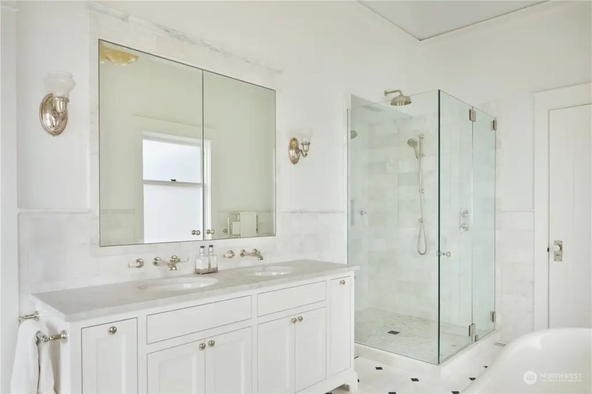 A glass-enclosed walk-in shower with marble tile.