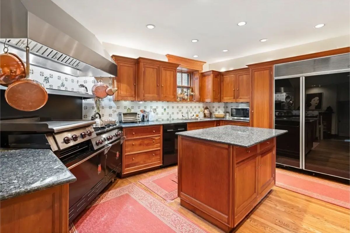Rich wooden cabinetry and a central granite-topped island, creating a warm and inviting atmosphere.