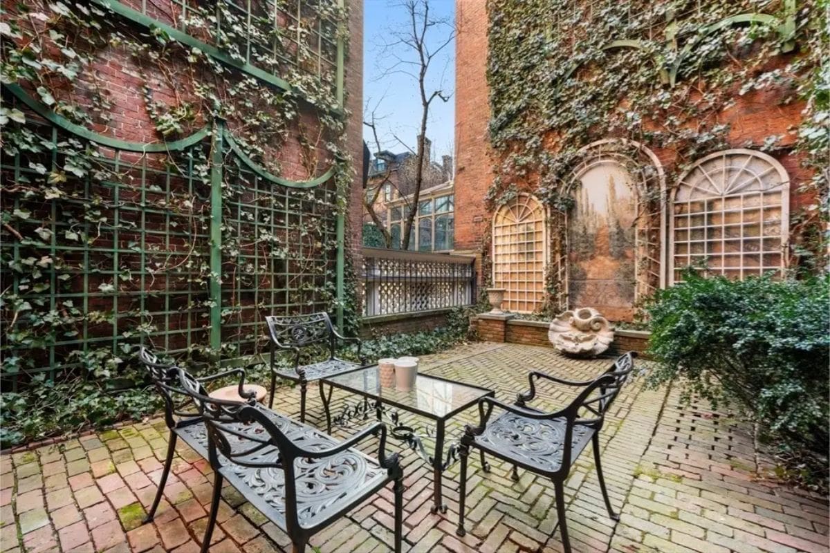 An intimate seating area surrounded by ivy-draped brick walls and decorative green latticework.