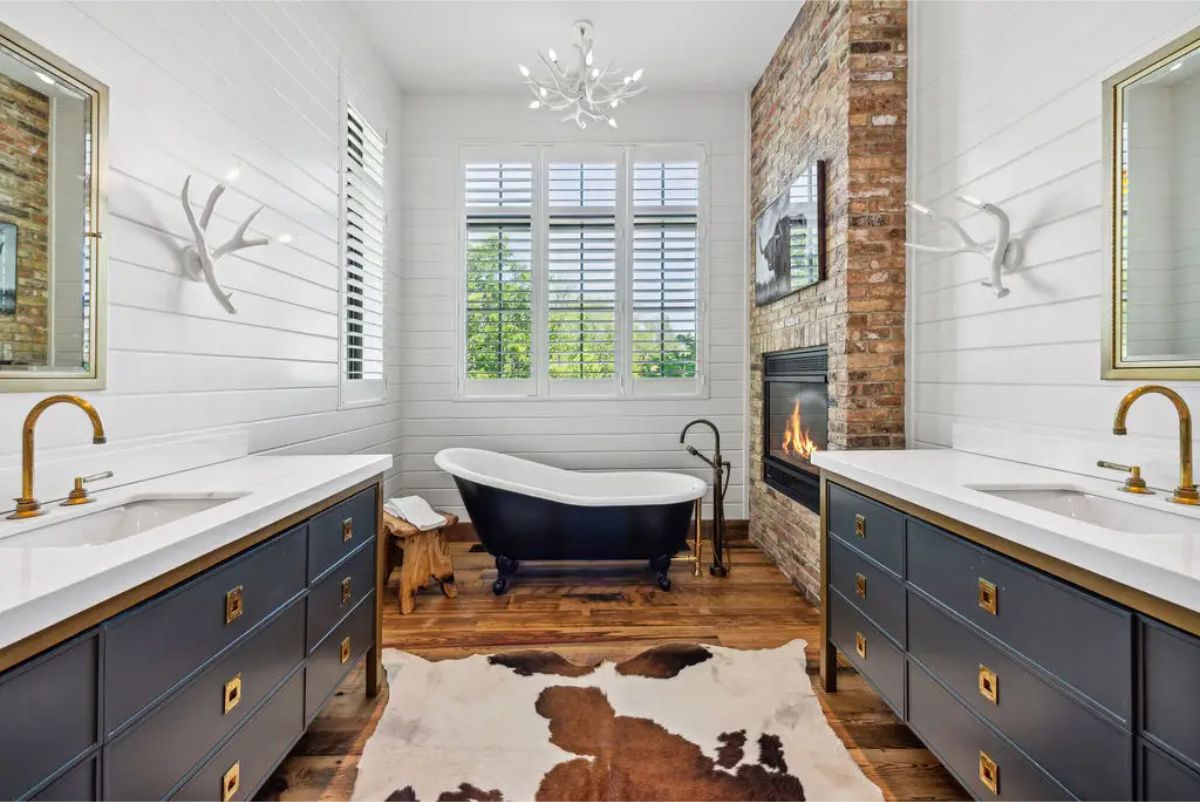 A freestanding clawfoot bathtub as the centerpiece, complemented by a double-sided brick fireplace for added warmth and ambiance.