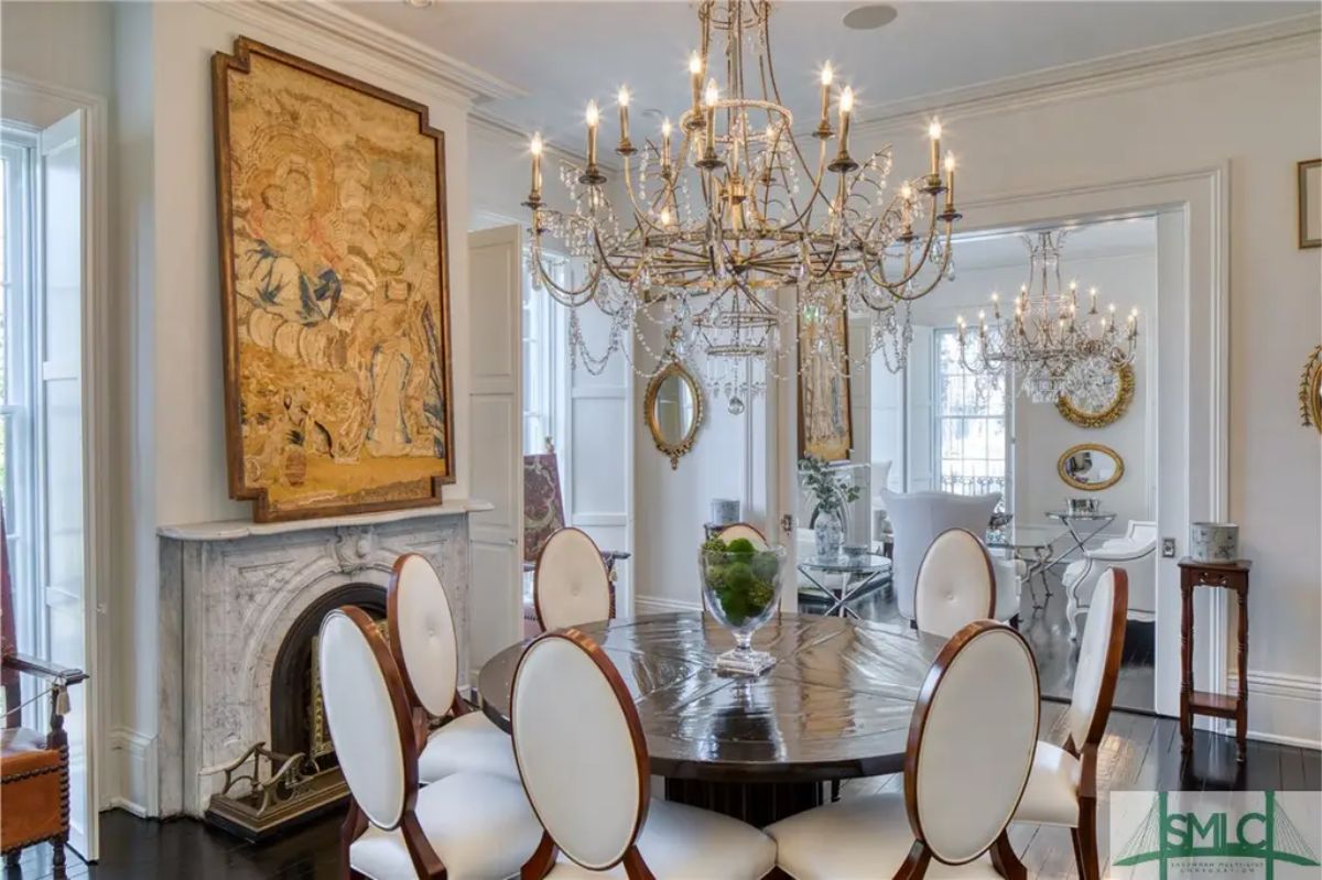 Wooden table surrounded by white upholstered chairs with dark wood trim.