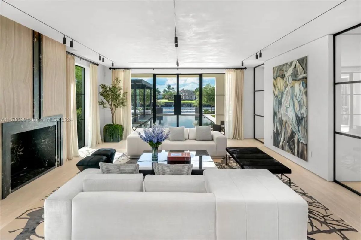 Bright and modern sitting area with a fireplace, large artwork, and glass doors leading to the outdoor pool. 