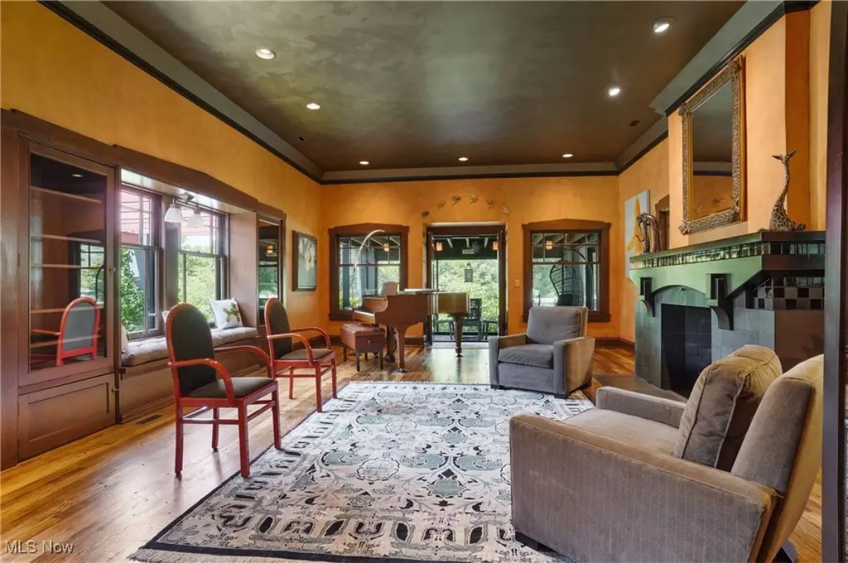 Warm orange walls, dark wood trim, and a black tiled fireplace as its focal point.