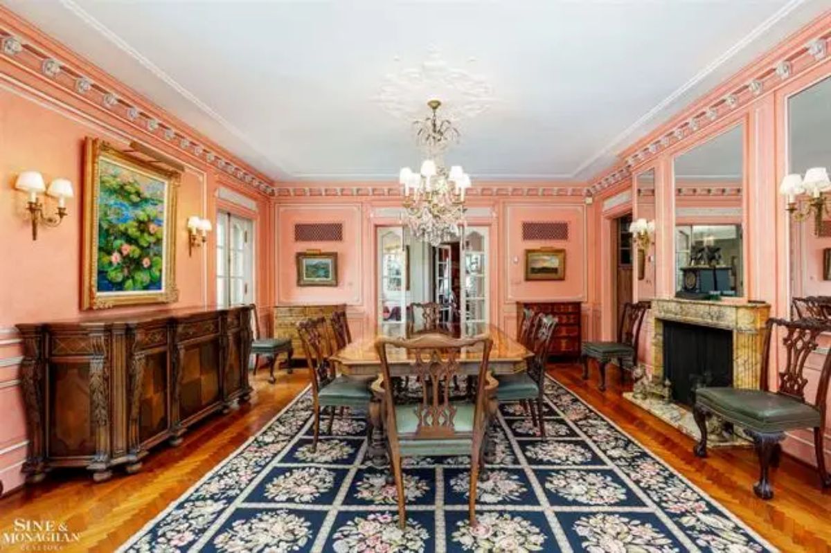 Dining room with coral-colored walls and intricate crown molding.