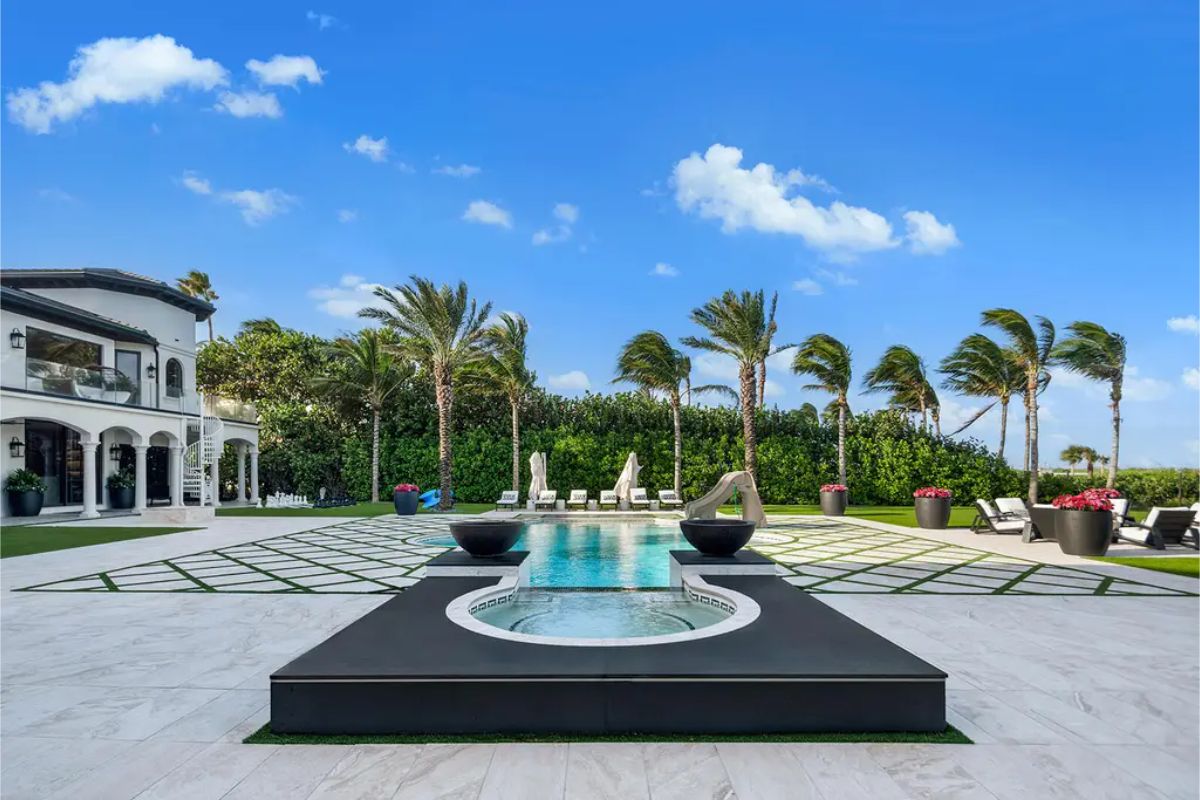 Elegant backyard featuring a geometric pool design, tall palm trees, and a relaxing spa area. 