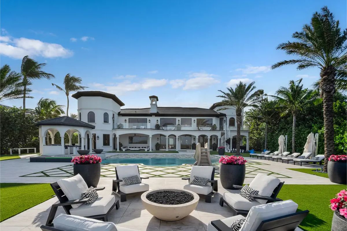 Grand estate with a Mediterranean-style exterior, lush landscaping, and a luxurious poolside lounge area. 
