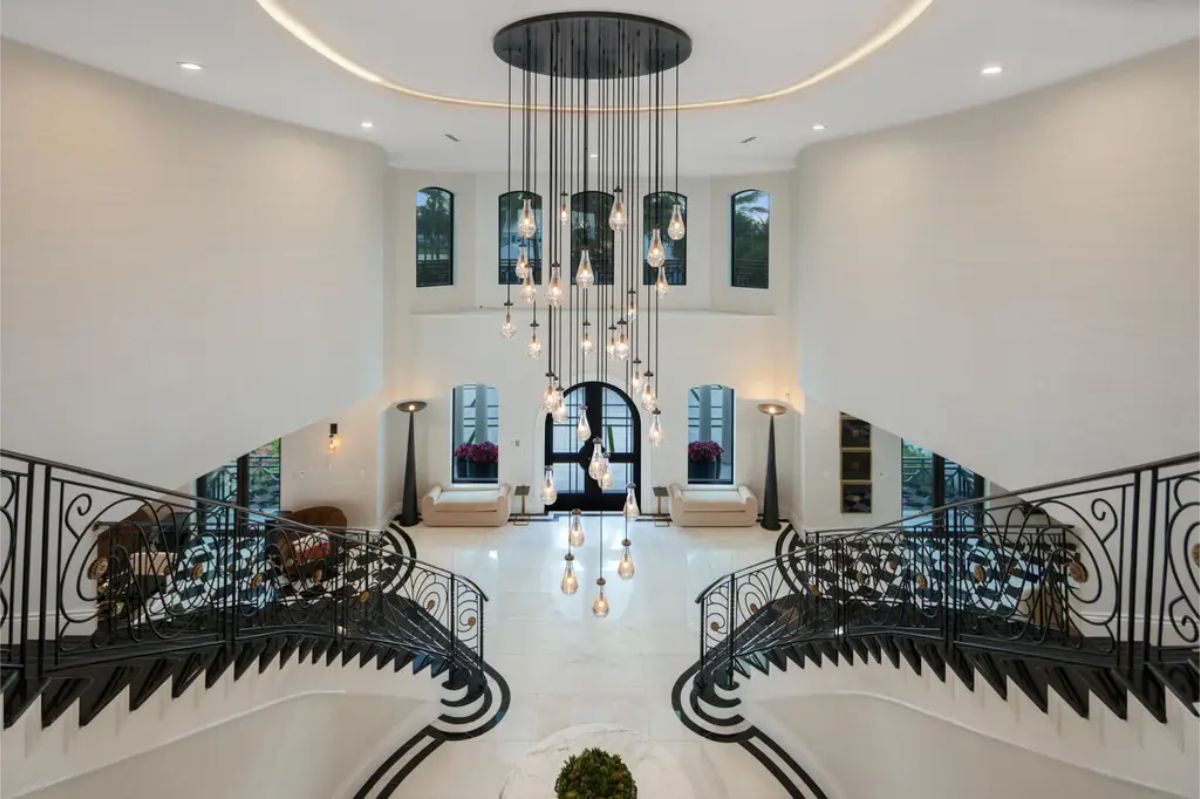 Ornate spiral staircase from a second-floor view, overlooking the grand entryway and a custom light fixture. 
