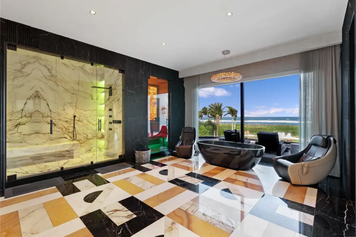Spacious spa-like bathroom with a glass-enclosed shower, black soaking tub, and oceanfront views. 