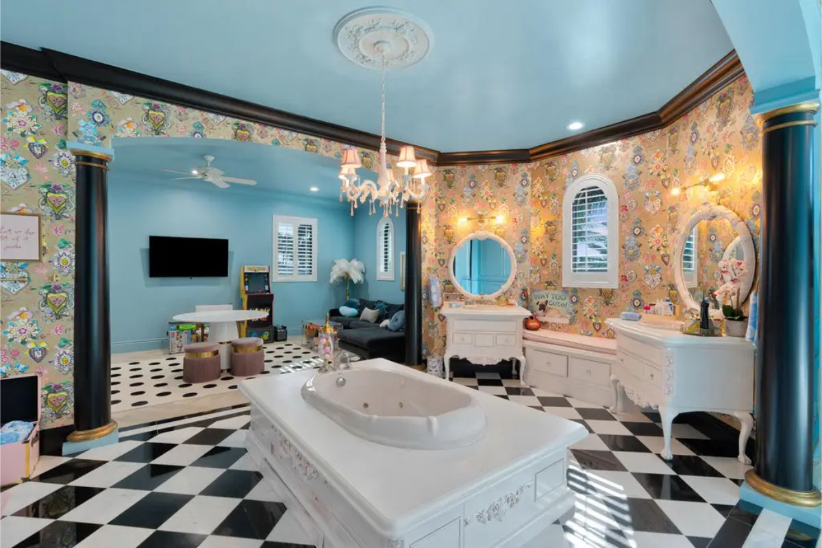 Opulent bathroom featuring a grand soaking tub, floral-patterned wallpaper, and elegant vintage-style vanities. 
