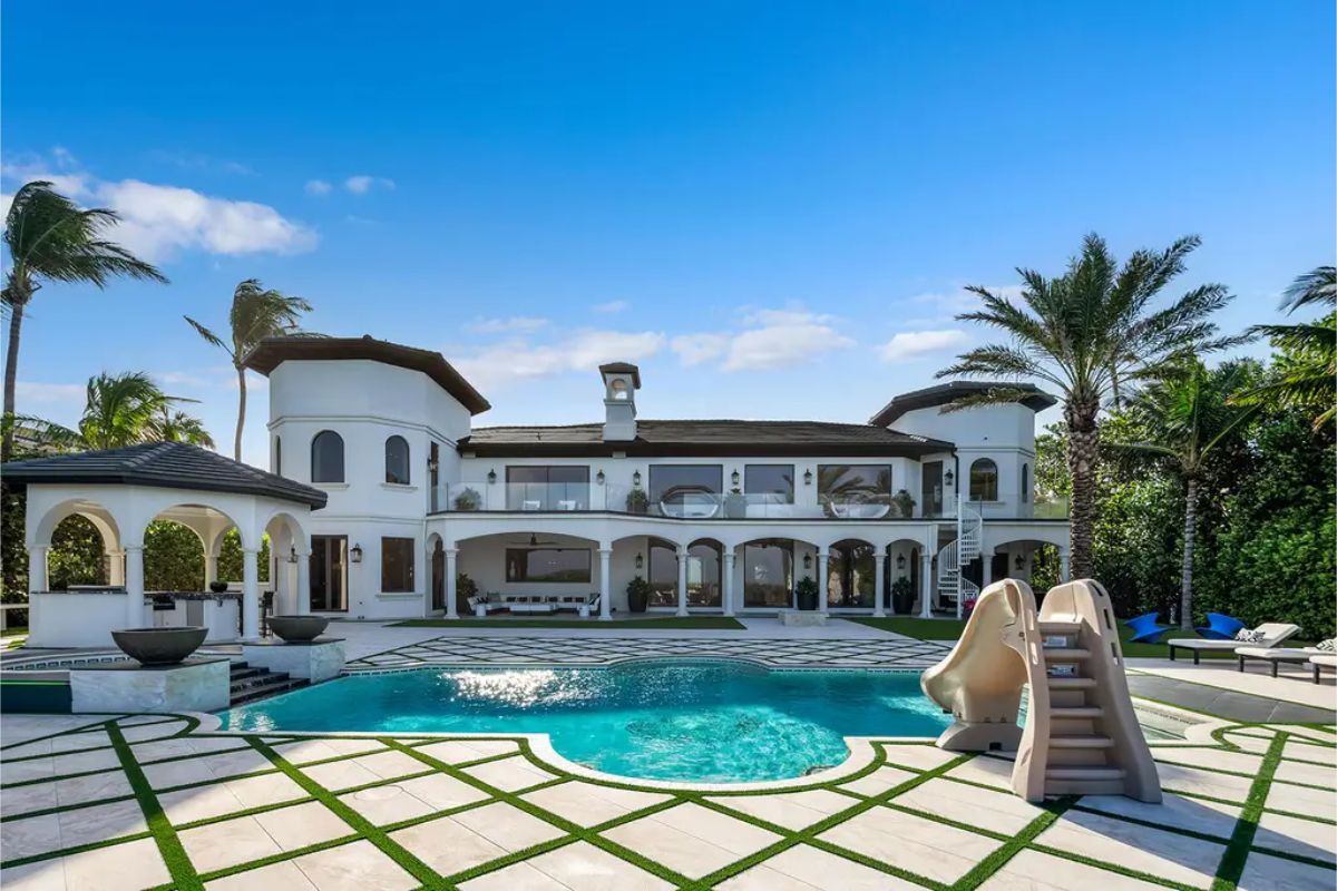 Lavish mansion exterior with a well-designed pool, lush gardens, and a stylish outdoor living area. 
